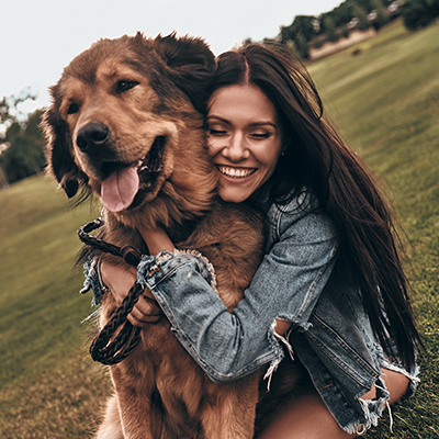 a happy woman is hugging her pet after dog chiropractic care treatment